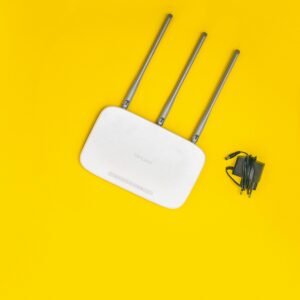 White router with three antennas and cables on bold yellow background, ideal for tech concepts.