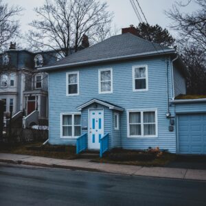 A cozy blue house with garage in a suburban neighborhood, showcasing quaint architectural style.